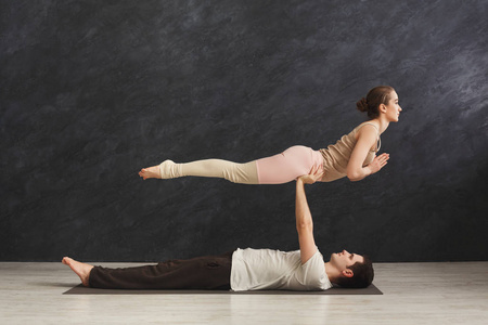 年轻夫妇在垫子上练习 acroyoga