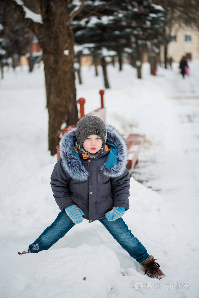 可爱的小滑稽的孩子在五颜六色的冬天衣裳有乐趣与雪室外在雪期间户外
