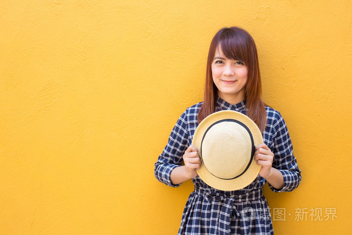 微笑的女人穿着连衣裙手拿着黄色水泥瓦上的帽子