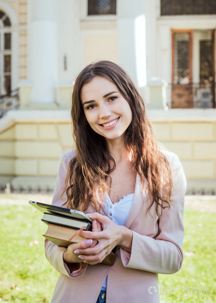年轻的白人女学生书与平板电脑在校园里学生在校园面积研究