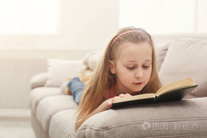 漂亮的feamle孩子看书躺在沙发上在家