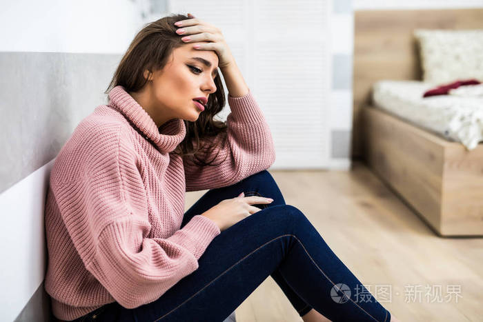 美丽的女人感觉不好, 头痛的痛苦坐在客厅地板上