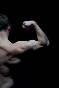男子运动员半躯干, 后视图。运动员柔韧的手臂肌肉。健美运动员显示二头肌和三肌。健身房锻炼和训练活动。体育力量和个人护理概念