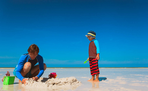 父亲和小儿子在沙滩上玩沙