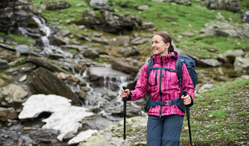 特写肖像的快乐年轻女子背包和徒步在山上的棍子。概念健康和积极的生活方式