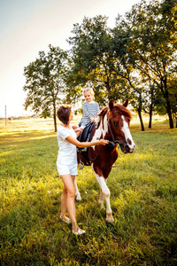 与她的母亲走附近骑在马背上的小女孩
