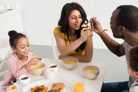 妻子和丈夫在与孩子们一起吃早饭时互相喂养