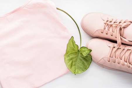 粉红色的运动鞋, 粉红色的罐顶和花叶。概念春天, 夏天, 温暖。平躺