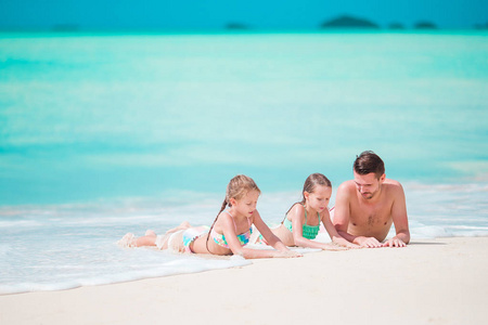 父亲和小朋友们享受海滩夏日的热带假期。家庭在海滩上玩耍