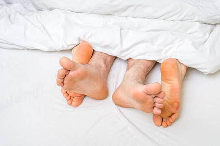 在一张床在毯子下的四只脚的特写镜头照片