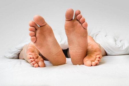 在一张床在毯子下的四只脚的特写镜头照片