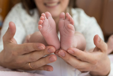 父手里轻轻地捧着婴儿的脚从下面照片
