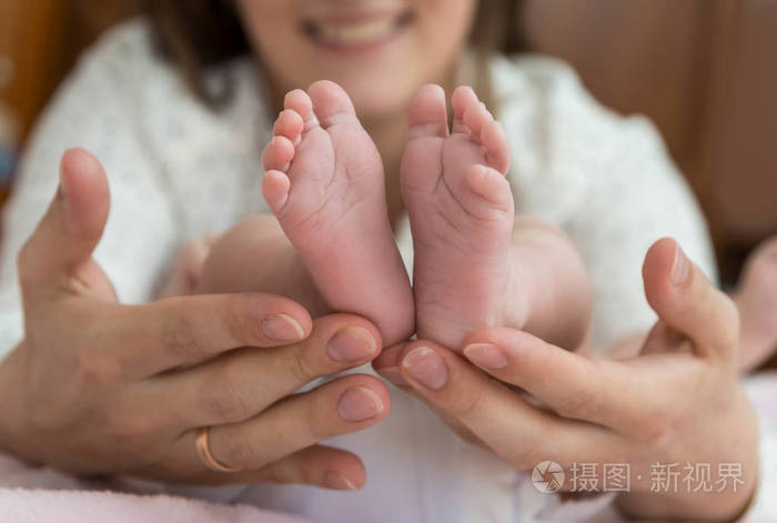 父手里轻轻地捧着婴儿的脚从下面