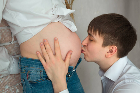 男人亲吻他怀孕的妻子在肚子里