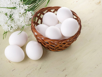 复活节背景。鸡蛋在一个木制篮子和第一个春天白色花在木质背景上