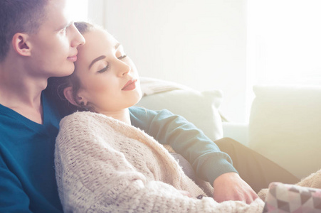 爱的年轻夫妇拥抱和躺在沙发上在家里