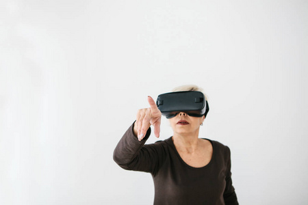 一个戴着虚拟现实眼镜的老年妇女。使用现代技术的老年人