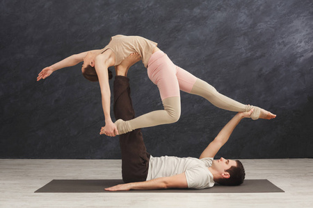 年轻夫妇在垫子上练习 acroyoga