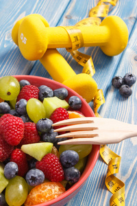 新鲜水果沙拉叉和哑铃 健康的生活方式和营养概念厘米