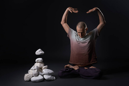 男人坐在地板上在瑜伽姿势影棚拍摄照片