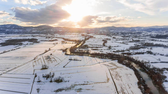 夕阳下的冰雪覆盖的乡村河流鸟瞰图