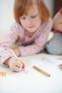 女孩画用彩色铅笔躺在地板上