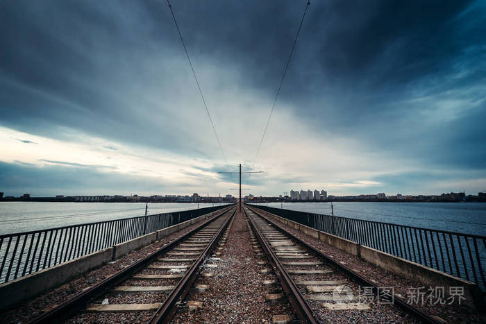 轨道通过桥梁与剧烈多云蓝天背景在城市, 透视