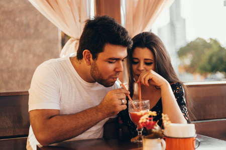 年轻情侣坐在餐厅里, 喝着五颜六色的饮料, 聊天, 享受着彼此共度的时光。