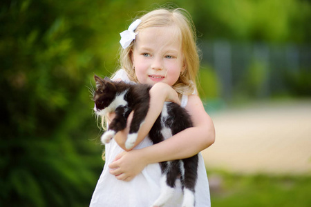可爱的小女孩与她的宠物小猫在温暖的夏天天。儿童和动物