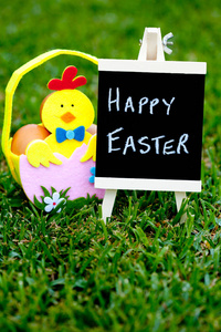 复活节彩蛋狩猎蛋感到与小鸡装饰草背景与黑板上篮