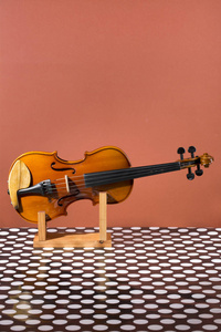 棕色背景上的木架上的小提琴