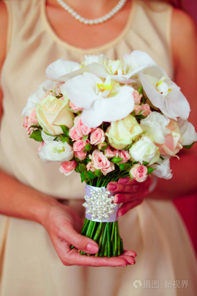 年轻的新娘穿着漂亮的连衣裙, 手捧着花束