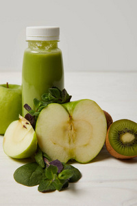 一瓶绿色排毒冰沙, 苹果, 猕猴桃, 薄荷和白色木质表面