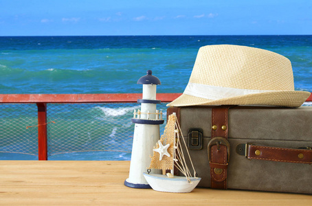 旅行者古董行李, 小船和软呢帽帽子在木桌前面在海风景。假日和假期概念