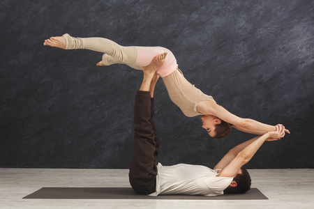 年轻夫妇在垫子上练习 acroyoga