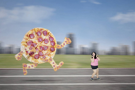 大比萨追逐肥胖的女人在赛道上图片