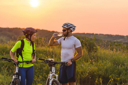 骑自行车的人和女人在旅途中停下来喝水。