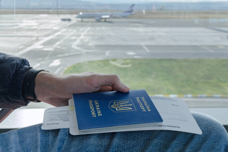 飞机免扣男子手持有乌克兰外国护照与机票飞机在后台停放的飞机.