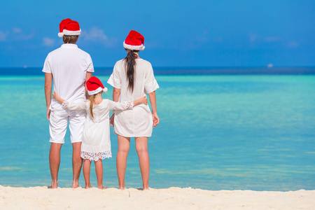 幸福的家庭，三在圣诞节假期的海滩上圣诞老人的帽子