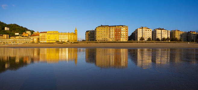 圣塞巴斯蒂安城 Donostia 在日落时映在 la zurriola 的海滩上。