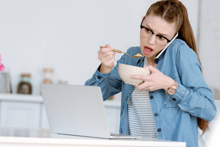 震惊女性 teleworker 吃早餐, 而谈论智能手机和看笔记本电脑