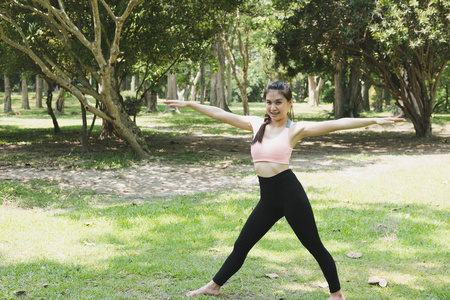 年轻的亚裔女子，练瑜伽在户外在早上公园。浓