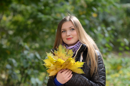 年轻女子上了秋天的叶子在手