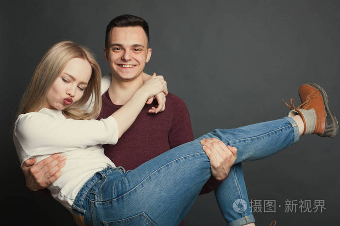 的肖像在工作室在黑暗背景下摆姿势那家伙把心爱的人抱在怀里微笑着