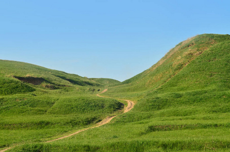 被践踏的路径，通过精彩的绿色山区地形景观。美丽的园景的救济空间与薄的路径的照片