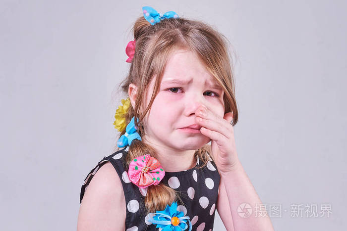 一个美丽的小女孩 带着悲伤的表情 哭着 用双手拭去泪水.
