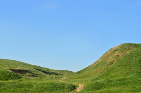 被践踏的路径，通过精彩的绿色山区地形景观。美丽的园景的救济空间与薄的路径的照片