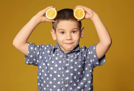 有趣的小男孩与柑橘果在颜色背景