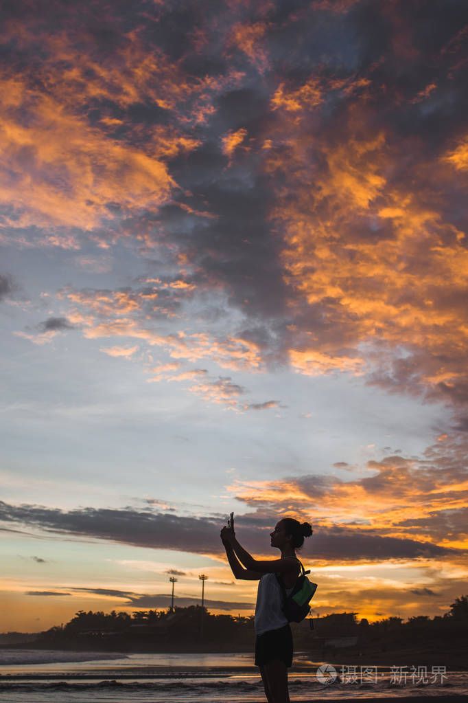 女人拍照片的夕阳与红云