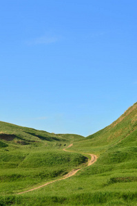 被践踏的路径，通过精彩的绿色山区地形景观。美丽的园景的救济空间与薄的路径的照片